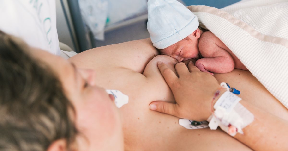 Tek porođena mama drži bebu na grudima prvi podoj