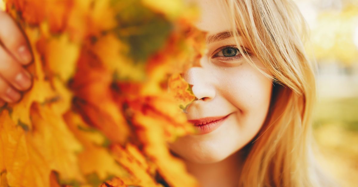 Devojčica iza jesenjeg lišća