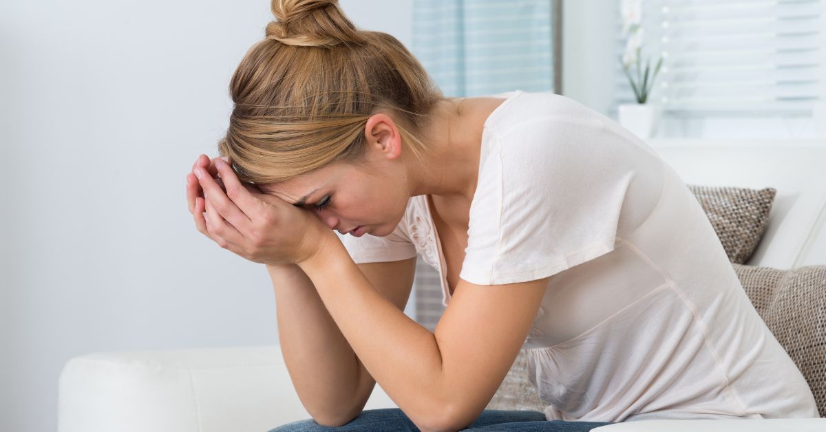 Žena sedi sa glavom u rukama