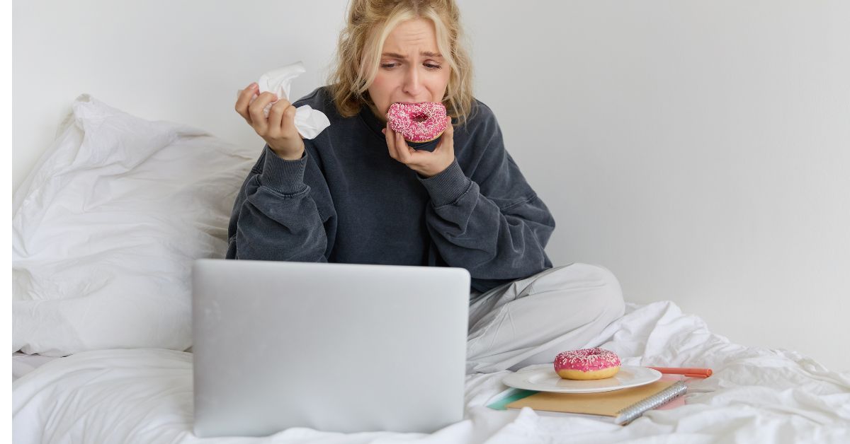 Žena jede krofnu u krevetu