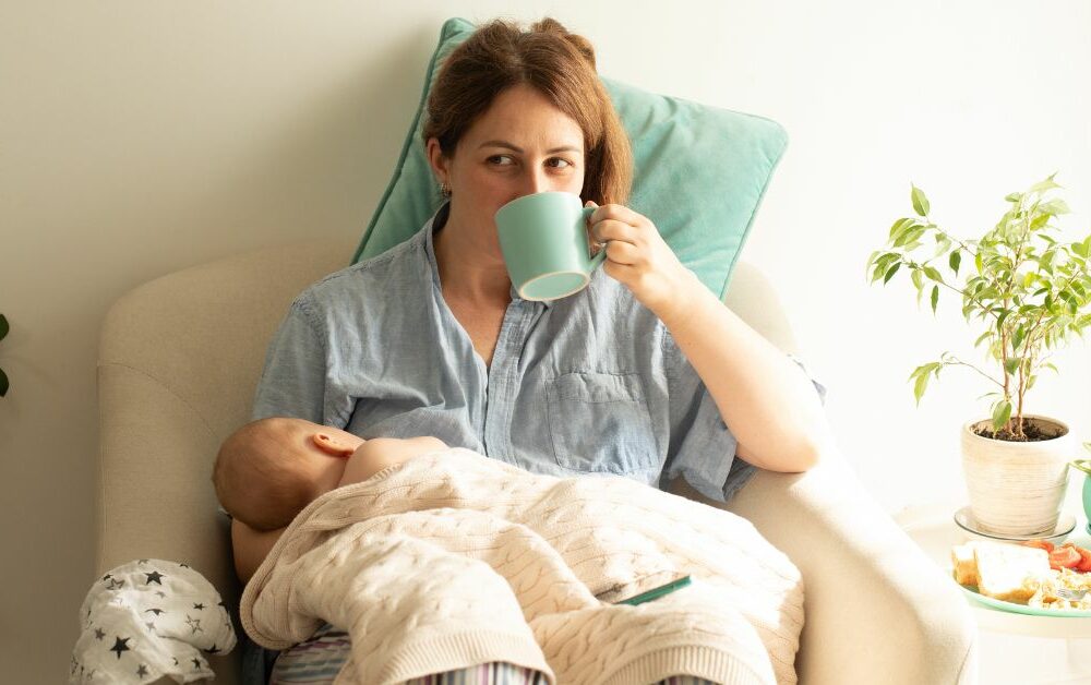 žena doji bebu i pije iz šolje