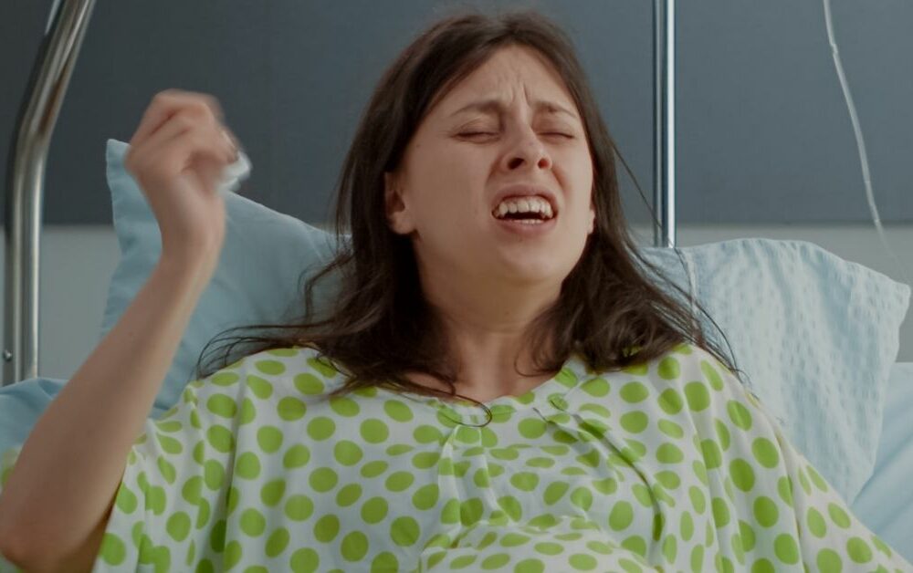 Žena u zelenoj spavaćici se porađa