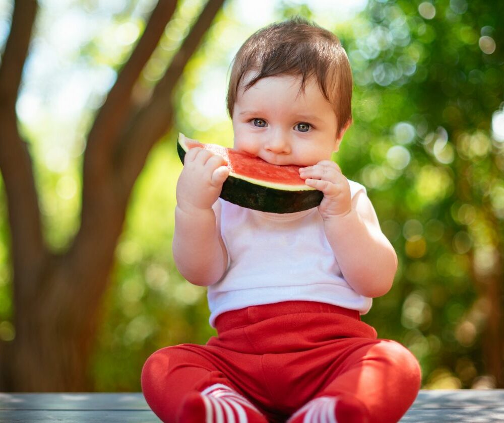 Beba sedi i jede krisku lubenice