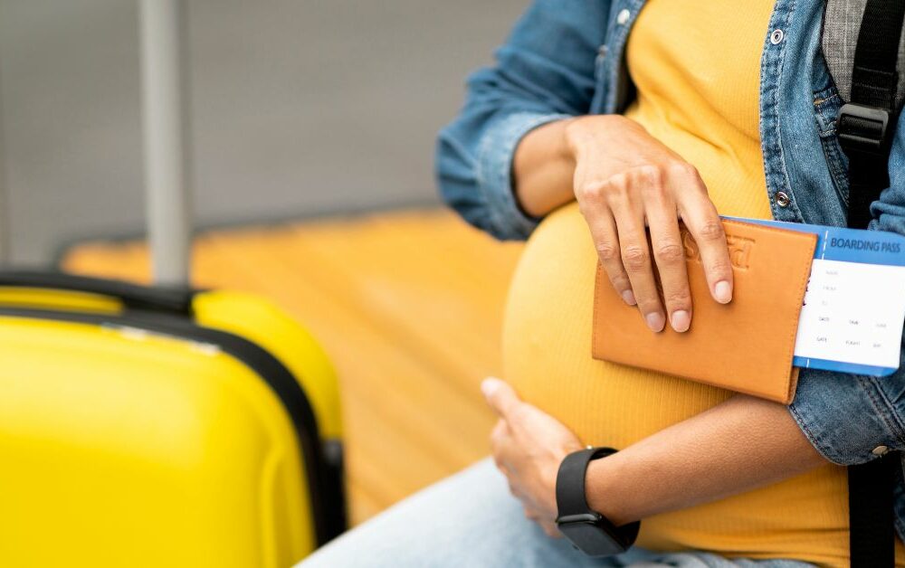 trudnica sa koferom drži pasoš na aerodromu